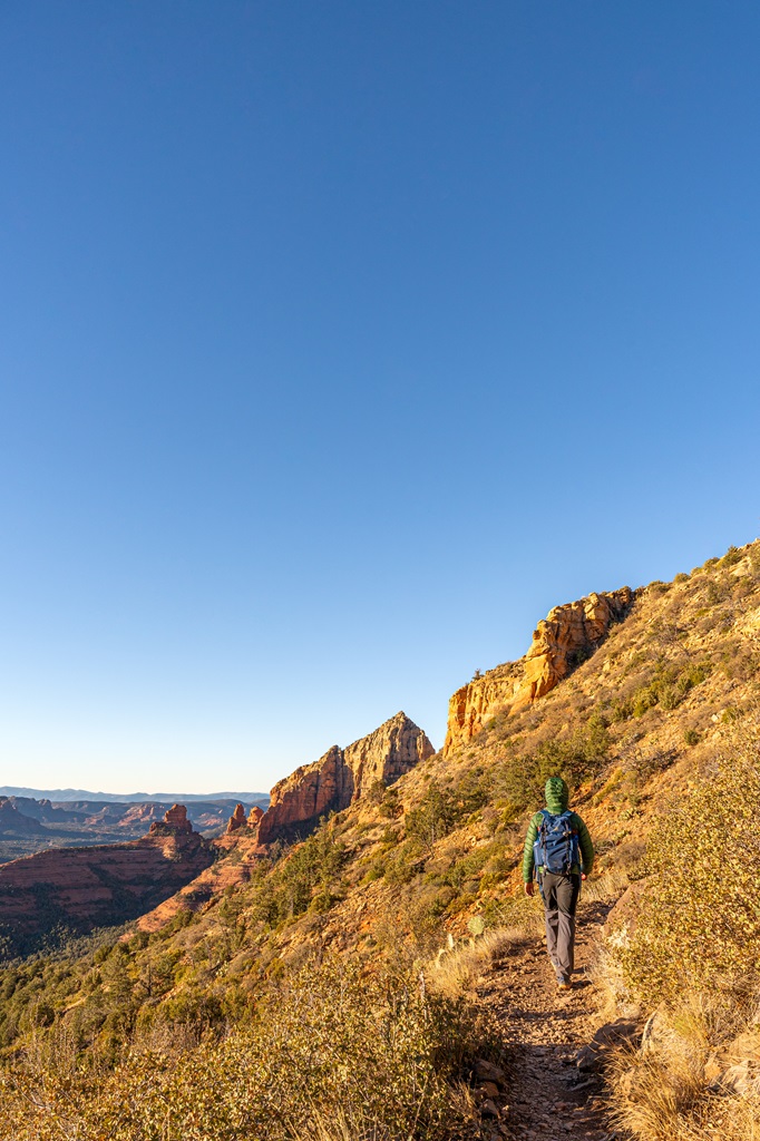 Man hiking along the Wilson Mountain Trail with scenic views in the distance.