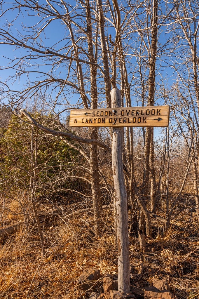 Trail sign at a junction at the top of Wilson Mountain in Sedona with arrow pointing towards Sedona Overlook and another arrow pointing towards North Canyon Overlook.