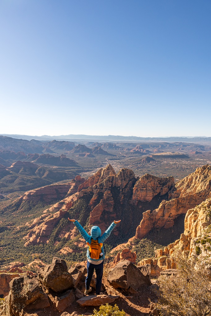 Woman standing at the Sedona Overlook on top of Wilson Mountain with hands in the air.