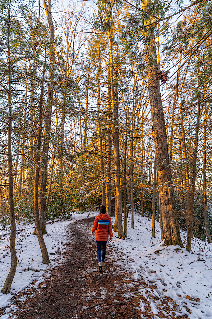 Woman hiking along the Long Point Trail in a light dusting of snow during winter.