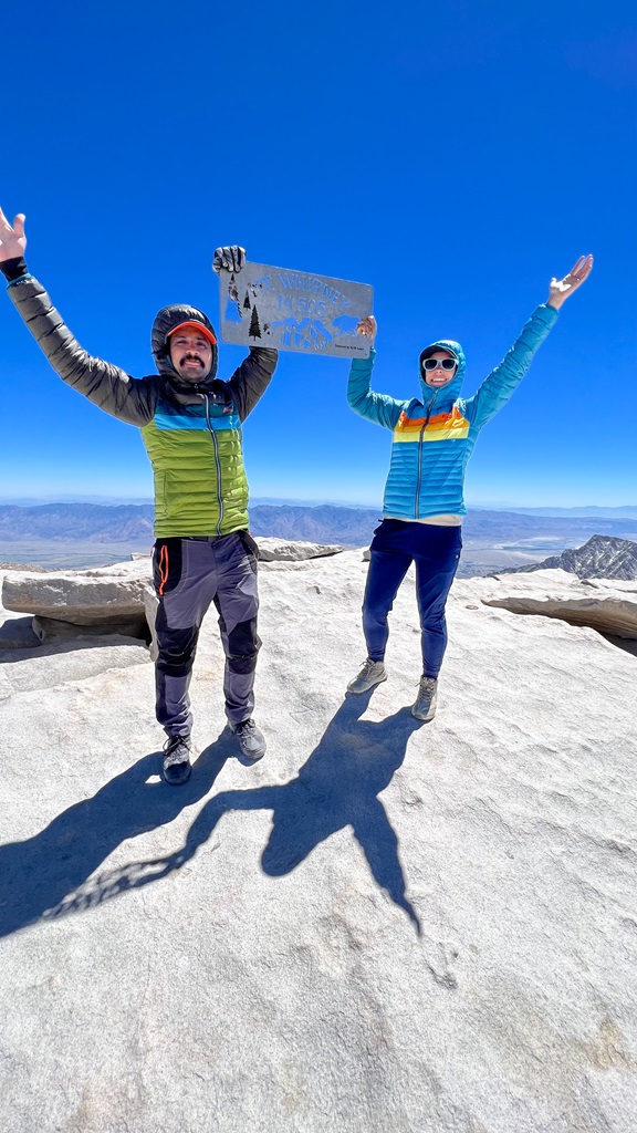 Man and woman holding the Mt Whitney summit sign.