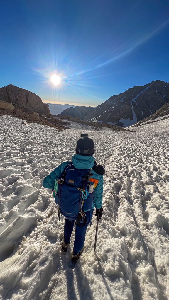 Woman standing on the steep, snow chute heading towards Trail Crest near Mt Whitney summit.