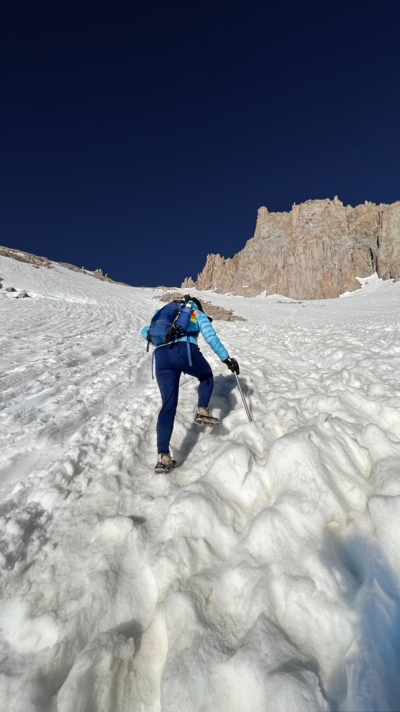 Woman climbing the steep, snowy chute towards Trail Crest near the summit of Mt Whitney.