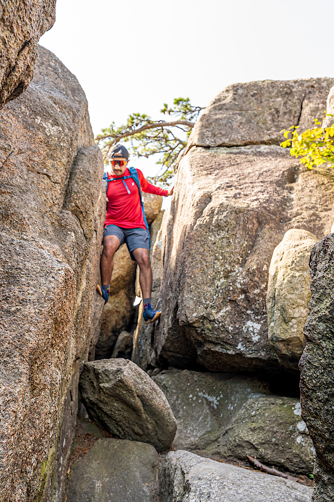 Man climbing down a narrow opening along the Old Rag Rock Scramble.