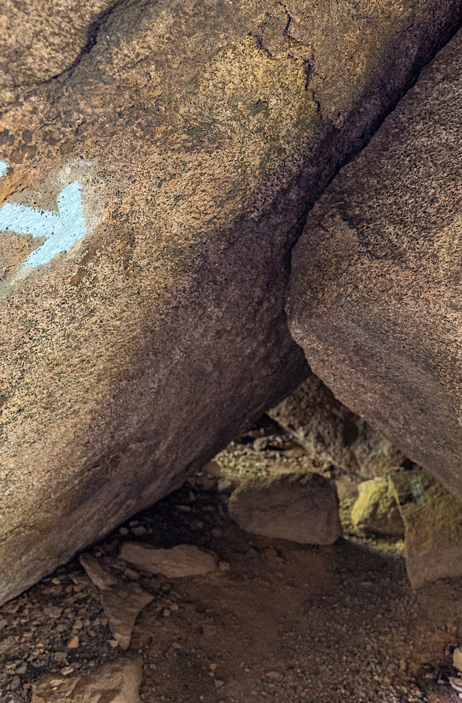 Fairly small natural tunnel with a blue arrow-shaped trail marker pointing towards the correct direction along the Old Rag Rock Scramble.