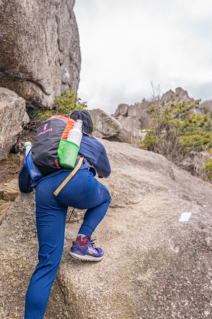 Woman climbing up a rock along the Old Rag Rock Scramble in Virginia.