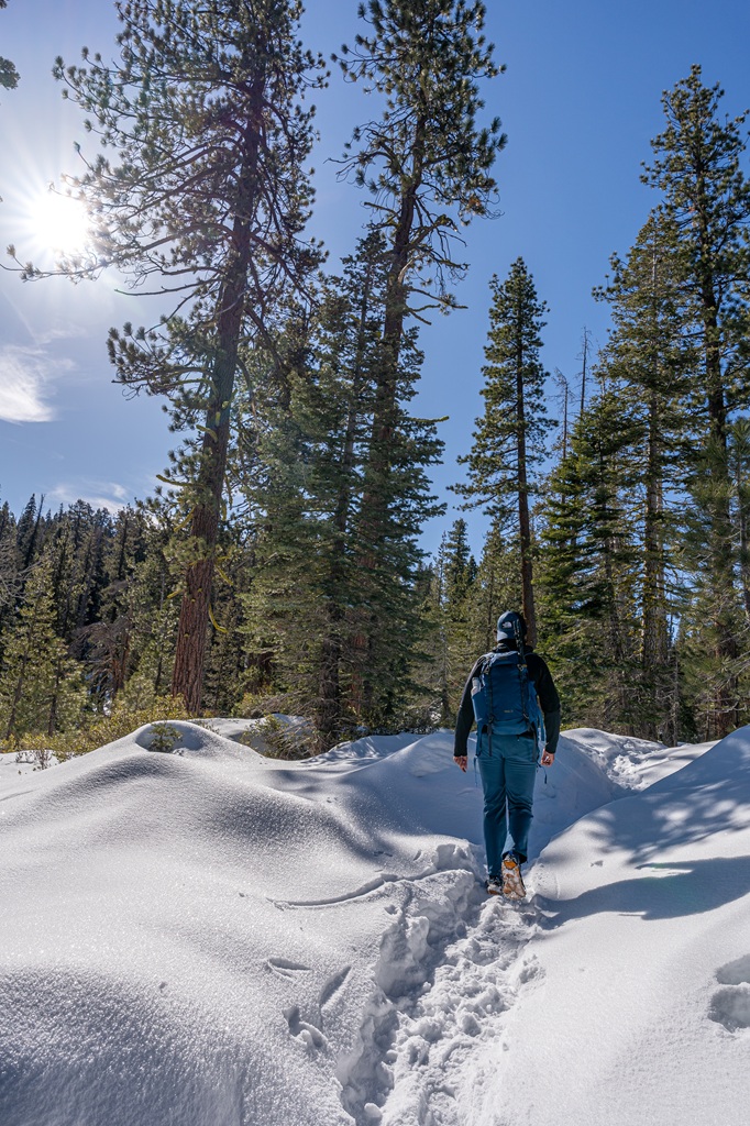 Man hiking along a snow-covered trail towards El Capitan in Yosemite National Park.