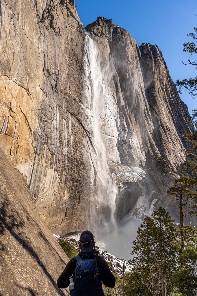 Man looking at Upper Yosemite Fall with a dusting of snow on the granite wall around the falls.