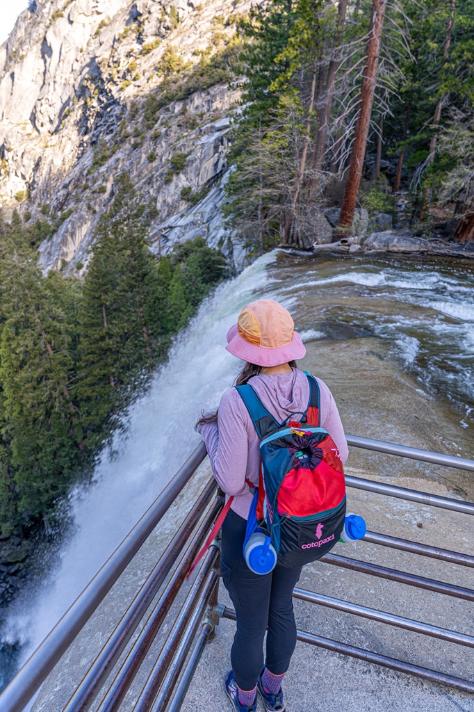 Woman standing at the top of Vernal Fall looking at the waterfall.