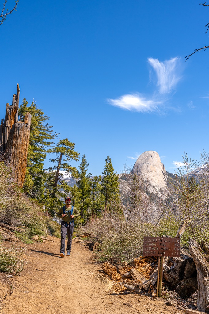Man hiking along the Panorama Trail with Half Dome in the background in Yosemite National Park.