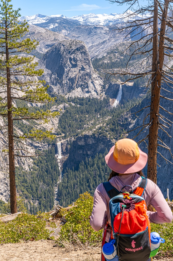 Woman looking at the view of Liberty Cap, Vernal Fall, and Nevada Fall from the Panorama Trail in Yosemite National Park.