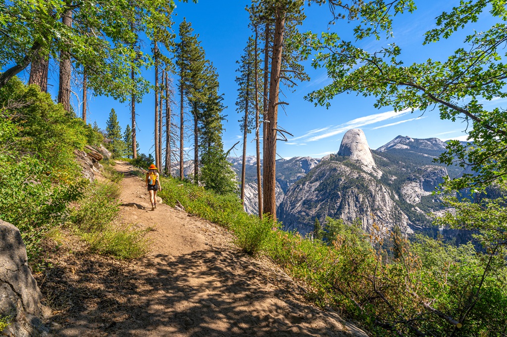 Woman hiking along the Panorama Trail with view of Half Dome in Yosemite National Park.