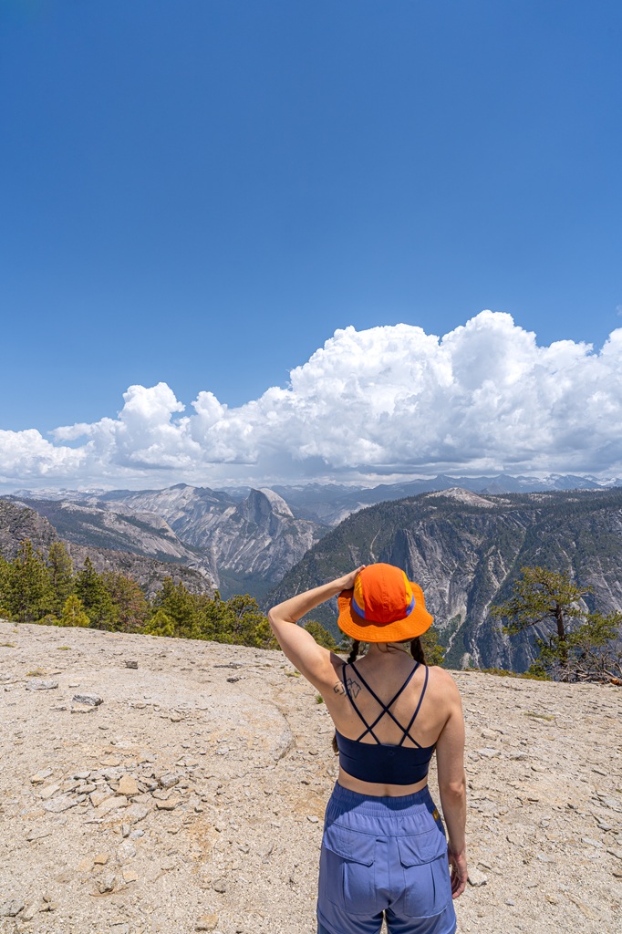 Woman standing on the top of El Capitan looking at the views of Half Dome, Sentinel Dome, and the distant Sierra Nevada peaks.