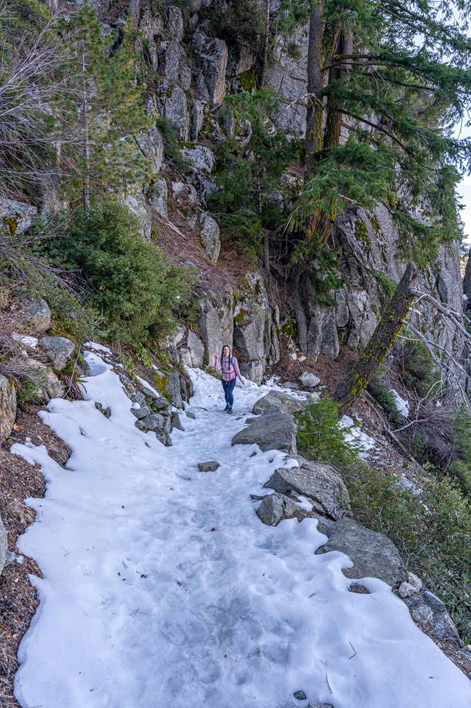 Woman posing for a picture on a snow and ice-covered section on the Four Mile Trail in Yosemite National Park.