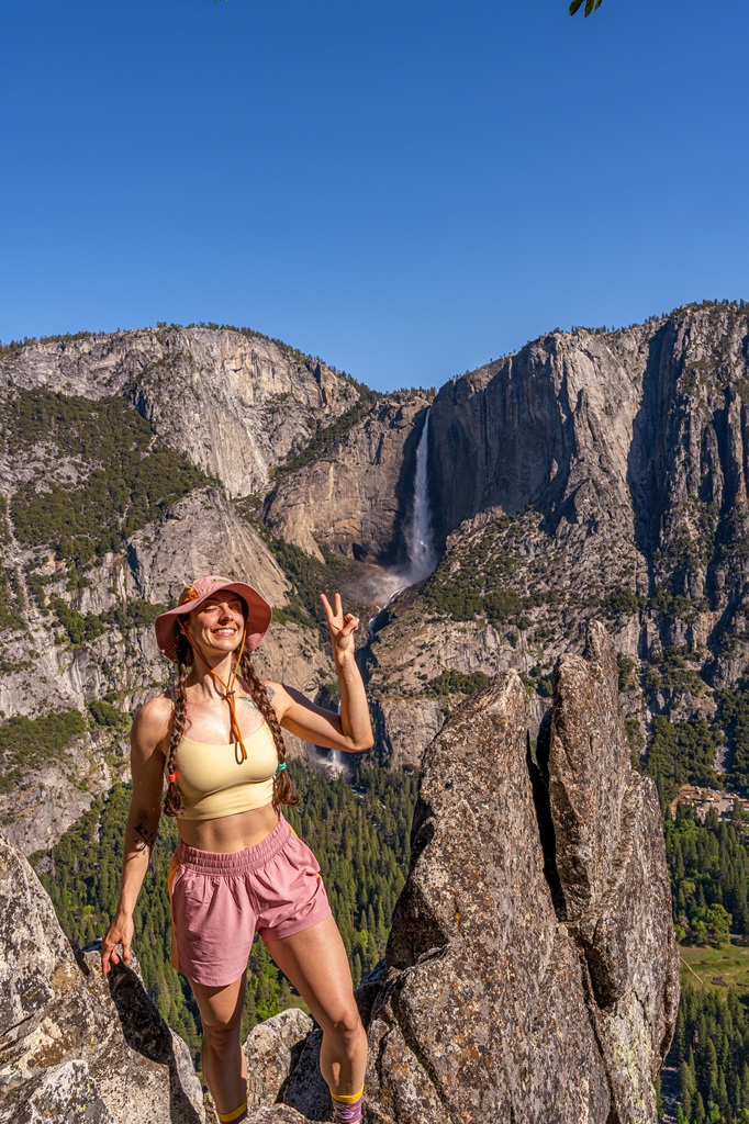 Woman posing for a picture on a viewpoint of Yosemite Falls off Four Mile Trail in Yosemite National Park.