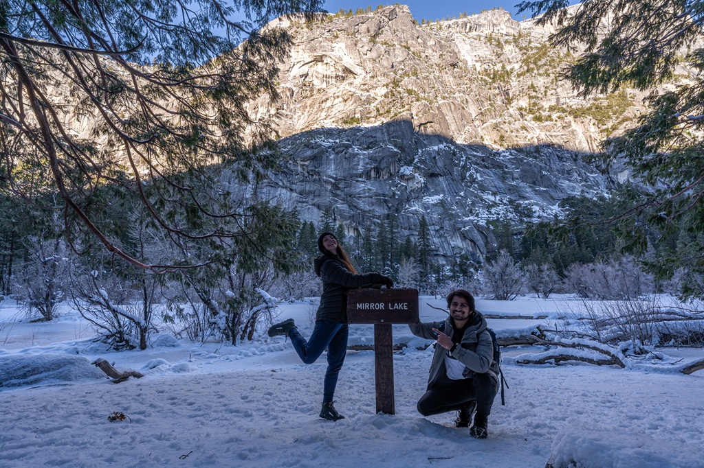 Man and woman posing for a picture by the Mirror Lake sign along the Mirror Lake Loop in Yosemite National Park.