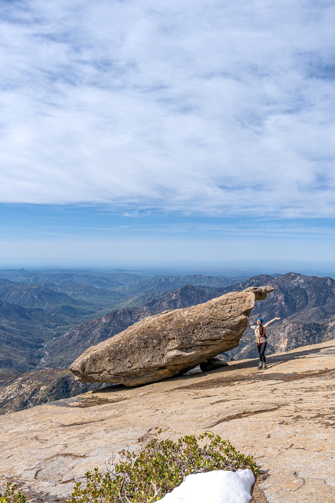 Woman posing for a picture with the Hanging Rock in Sequoia National Park.