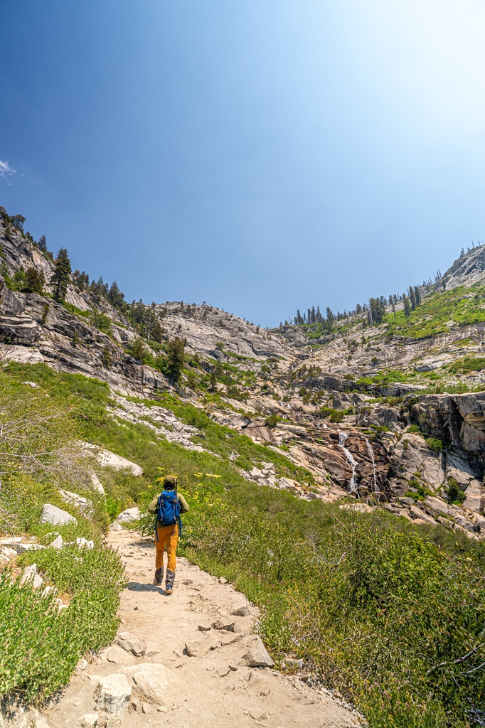 Man hiking along the trail with Tokopah Falls in the distance.