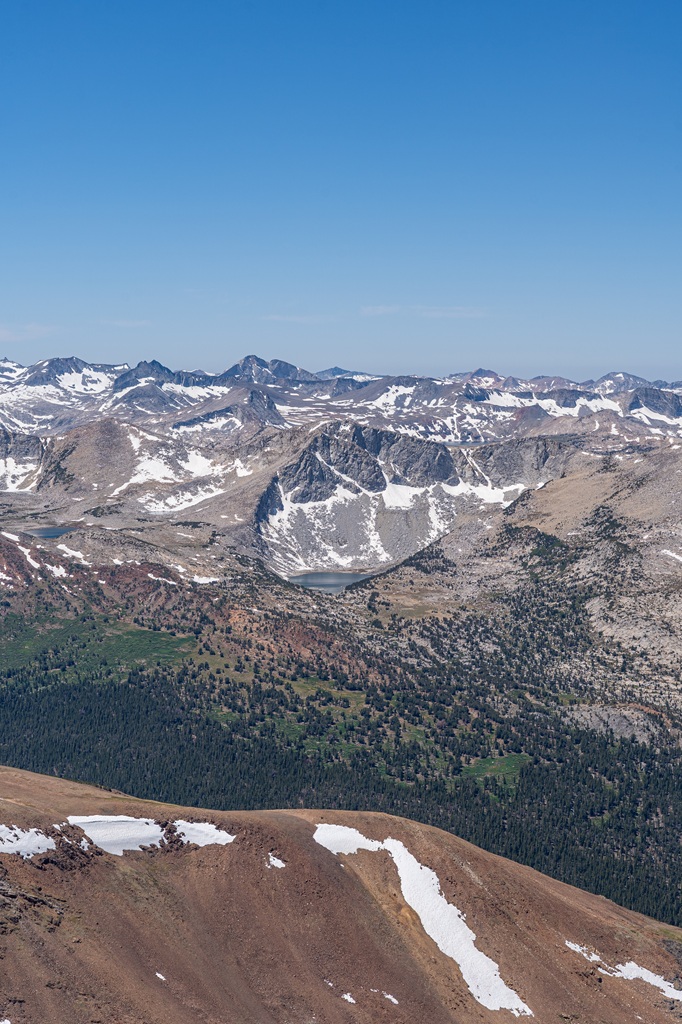View of an alpine lake surrounded by snowy peaks seen from the Mount Dana Trail.