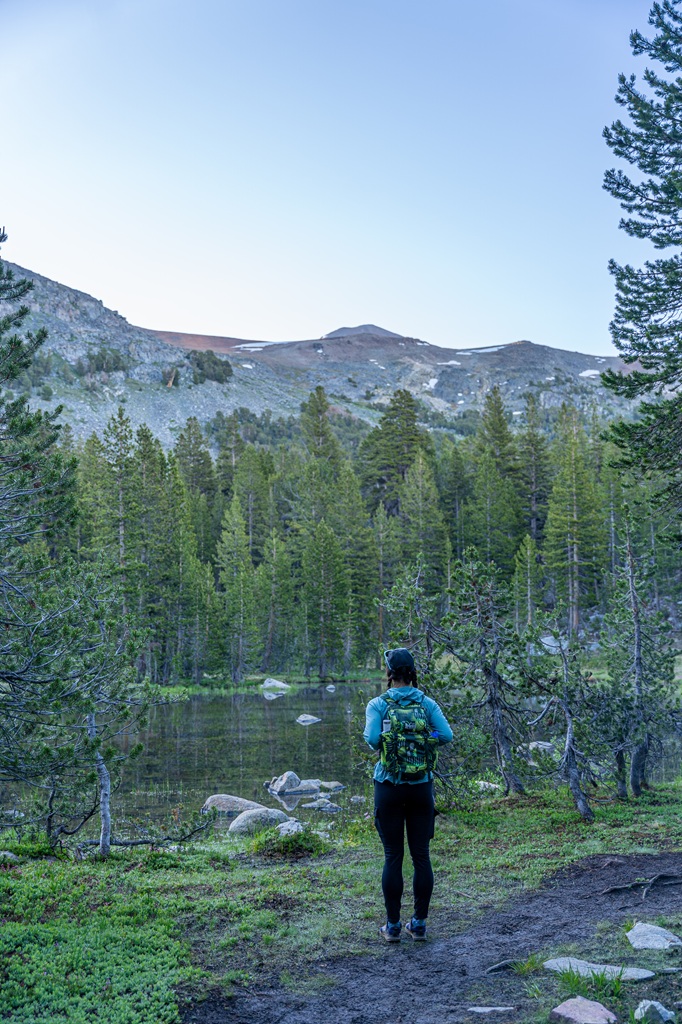 Woman standing near a small alpine lake along the Mount Dana Trail in Yosemite National Park.