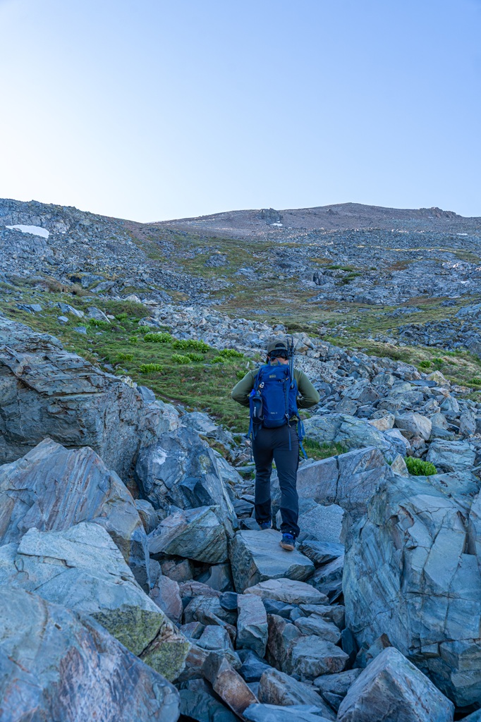 Man hiking over rocky terrain on the Mount Dana Trail in Yosemite National Park.