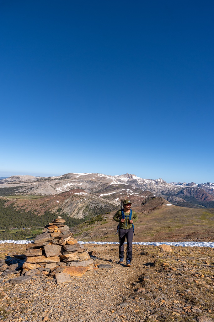 Man hiking on the Mount Dana Trail passing by a giant cairn.