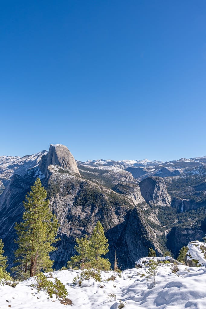 Jaw-dropping views from Glacier Point with mountain peaks covered in snow and Vernal and Nevada Falls flowing.