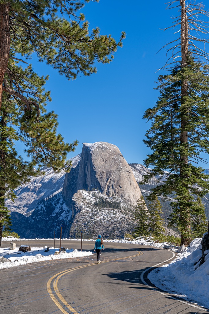 Woman walking along the Glacier Point Road after it was plowed and ready for re-opening.