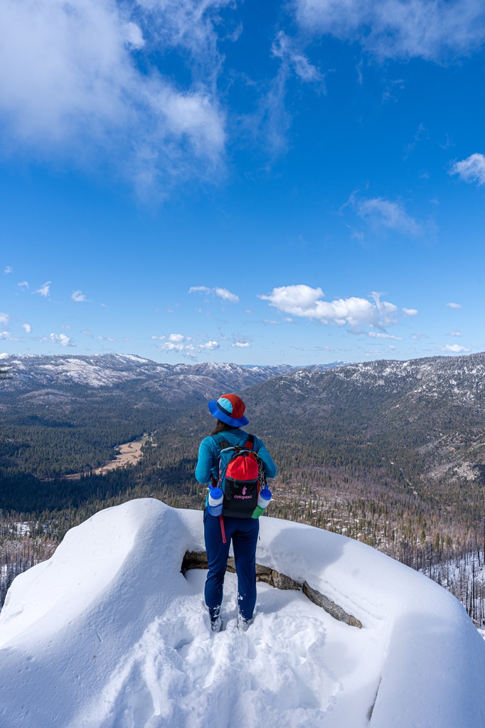 Woman standing at Wawona Point in the snow looking at the views of Yosemite.