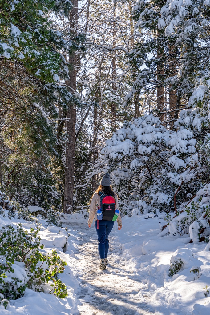 Woman hiking along a snow-covered trail in Yosemite National Park.