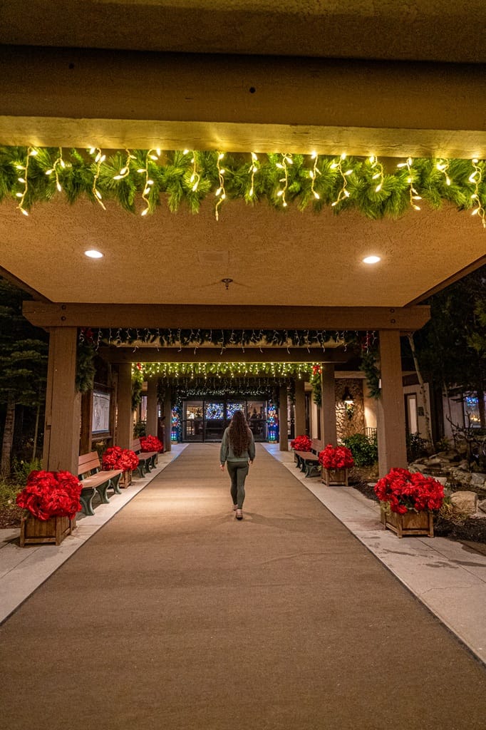 Woman walking towards the main doors to Tenaya Lodge at Yosemite decorated with holiday decor.