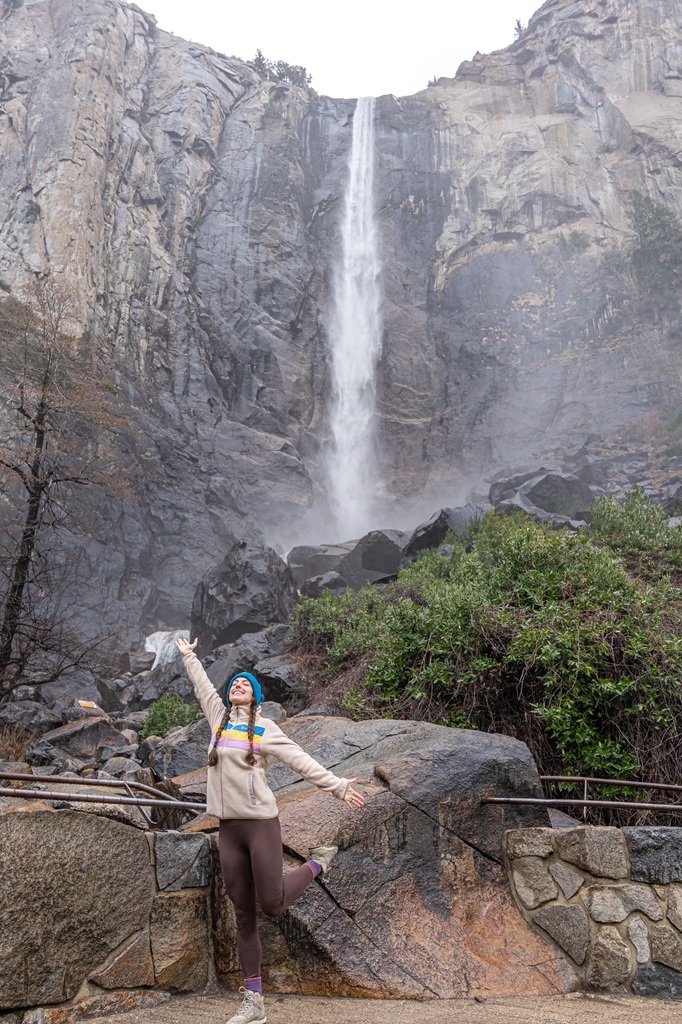 Woman posing for a picture at the Bridalveil Fall viewpoint in Yosemite.