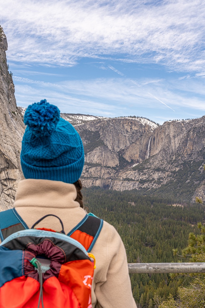 Woman looking at Yosemite Falls from a viewpoint in Yosemite in winter.