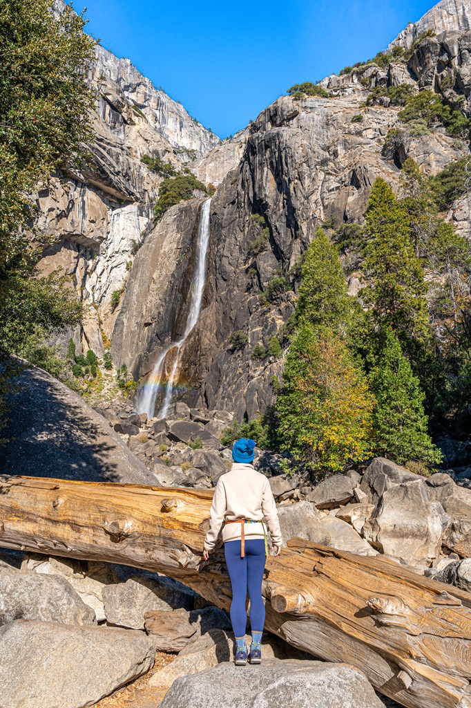 Woman standing on a rock at the Lower Yosemite Fall viewpoint in late fall.