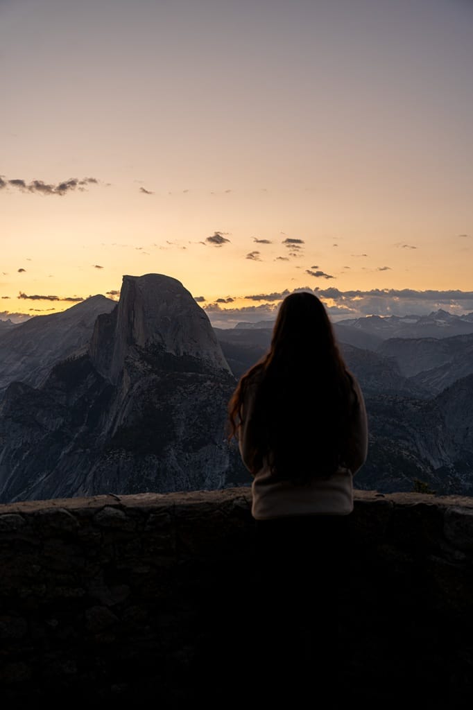 Woman watching sunrise from the Geology Hut at Glacier Point in Yosemite National Park.