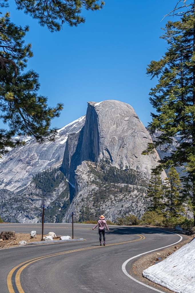 Woman walking on Glacier Point Road with Half Dome in the background.