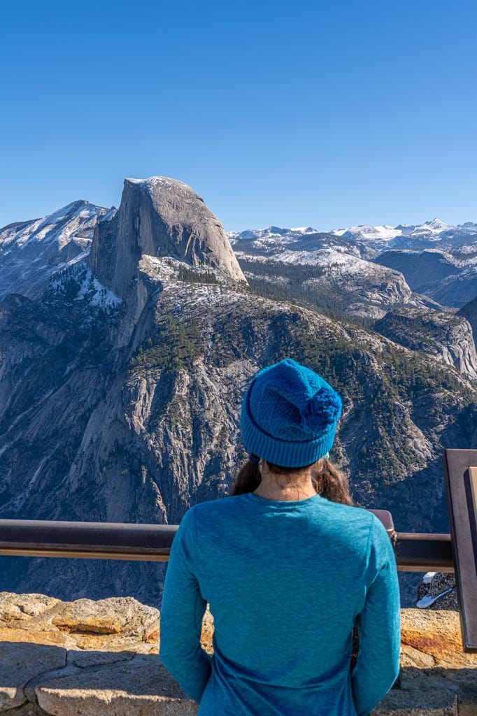 Woman standing at Glacier Point Overlook looking at the views in winter.