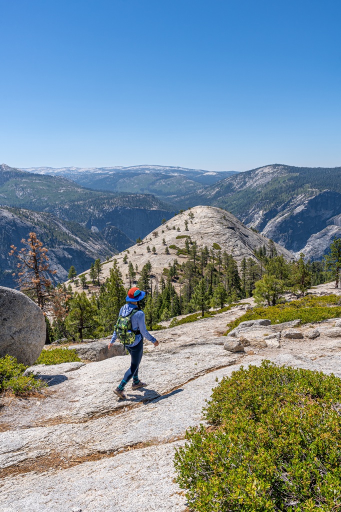 Woman hiking towards North Dome in Yosemite National Park.