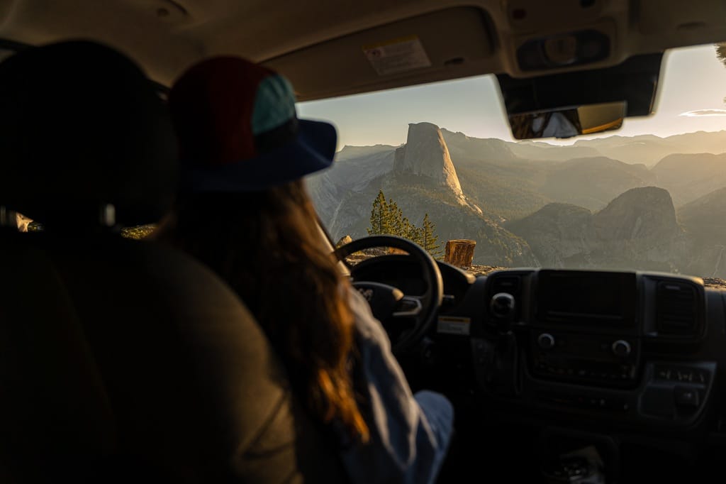 Woman sitting in the driver's seat of a van looking at the views at Washburn Point in Yosemite National Park.