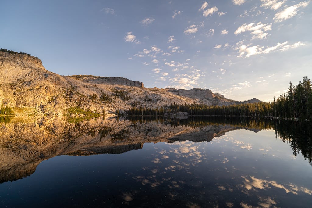 Granite mountains glowing at sunrise seen from May Lake in Yosemite National Park.